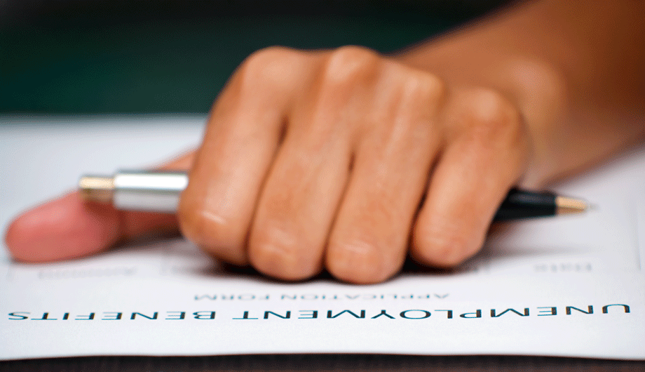 Close up of a hand holding a pen above an Unemployment Form