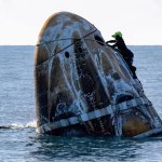 A support team member working on a capsule carrying astronauts that has landed in the ocean. 