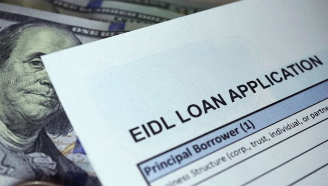 An Economic Injury Disaster Loan (EIDL) application form on top of cash.