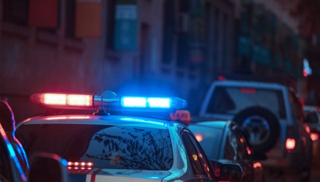 Police car with red and blue lights on the street outside a building