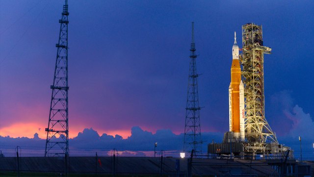 The Space Launch System rocket with the Orion spacecraft aboard atop the mobile launcher against a sunset backdrop
