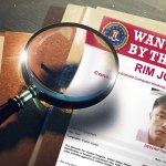 A "Wanted by the FBI" poster for Rim Jong Hyok atop a stack of papers with a magnifying glass