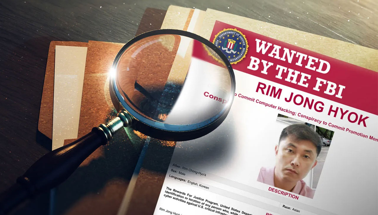 A "Wanted by the FBI" poster for Rim Jong Hyok atop a stack of papers with a magnifying glass
