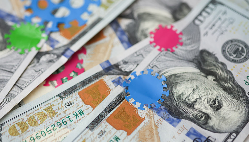 A stack of $100 bills covered in stickers of COVID-19 virus particles