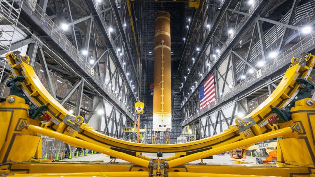 A massive crane lifting to vertical the Space Launch System Moon rocket inside the Vehicle Assembly Building