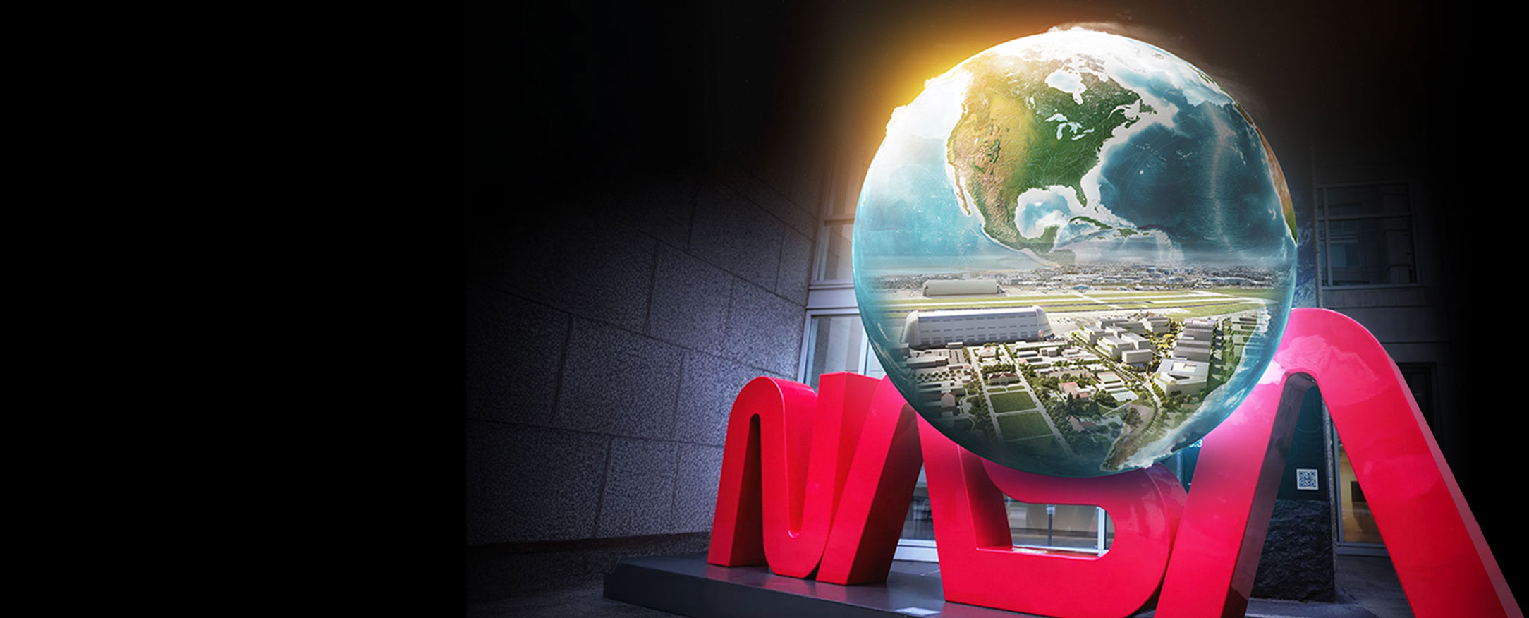 Illustration of a globe containing a bird's-eye view of buildings. The globe is on top of a sculpture of the red NASA "worm" logo.