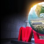 Illustration of a globe containing a bird's-eye view of buildings. The globe is on top of a sculpture of the red NASA "worm" logo.