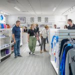 The inside of a NASA gift shop with several customers and NASA hats, shirts, and sweatshirts