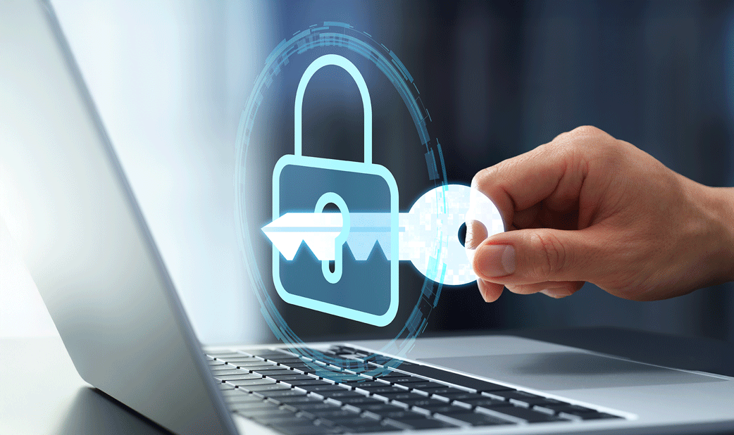 A lock hovering above a laptop, with a hand holding a key and placing it into the lock.